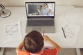 Boy making notes during online geometry lesson with teacher