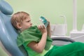 Boy man child at dentist in chair look at white teeth. Curious, serious look. Oral health and hygiene concept