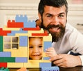 Boy and man on defocused background. Father and son with smiling faces hold toy bricks construction