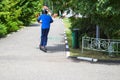 A boy, a man rides along the park road on a new modern electric scooter on batteries, standing on it with two legs