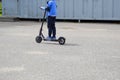 A boy, a man rides along the park road on a new modern electric scooter on batteries, standing on it with two legs Royalty Free Stock Photo