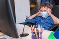 Boy with mask on his face is tired distance learning during quarantine covid-19