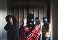 Boy with mask with teenagers gang indoors in abandoned building, showing finger gun gesture. Royalty Free Stock Photo