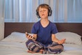 Boy meditates on bed using meditation app. sport, technology and healthy lifestyle concept Royalty Free Stock Photo