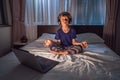 Boy meditates on bed using meditation app. sport, technology and healthy lifestyle concept Royalty Free Stock Photo