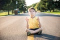 A boy is meditating sitting on the asphalt in the middle of the road. Spirit education relaxation concept