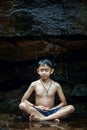 Boy meditating under a waterfall rocks in the woods somewhere.