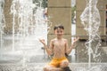 Boy meditating in water fountain find ZEN. Child playing with a city fountain on hot summer day. Happy kids having fun in fountain Royalty Free Stock Photo