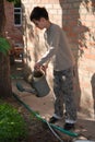 Boy with metal watering-pot against brickwall