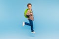 Boy in mid-stride with backpack, cheerful on blue background