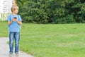 Boy with mobile phone in the street using game apps and looking around. City background. School, technology, leisure concept