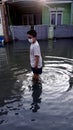 a boy in the morning sun, through the flood waters that inundate a settlement