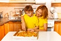 Boy and mother slicing pizza together in kitchen Royalty Free Stock Photo