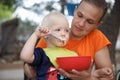 Boy in mothers lap in the campsite, eating in camping folding chair, having fun in the outdoors Royalty Free Stock Photo