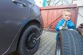 Boy mounted tires on a car. Royalty Free Stock Photo