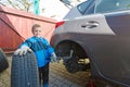 Boy mounted tires on a car. Royalty Free Stock Photo