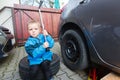 Boy mounted tires on a car. Royalty Free Stock Photo