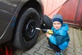 Boy mounted tires on a car. Royalty Free Stock Photo