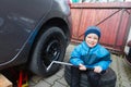 Boy mounted tires on a car. Royalty Free Stock Photo