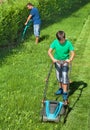 Boy mowing the lawn with man trimming at the edges Royalty Free Stock Photo