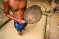 Boy in muddy water hold washed mined gemstone and rattan pan Royalty Free Stock Photo