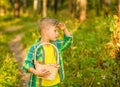 Boy with mushroom searches for the road in the forest