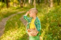 Boy with mushrooms searches for the road in the forest