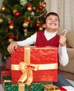 Boy near christmas tree and gift boxes, happy holiday and winter celebration, dressed in red Royalty Free Stock Photo