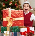 Boy near christmas tree and gift boxes, happy holiday and winter celebration, dressed in red Royalty Free Stock Photo