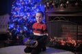 The boy next to a glowing blue Christmas tree and fireplace Royalty Free Stock Photo