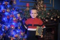 The boy next to a glowing blue Christmas tree and fireplace Royalty Free Stock Photo