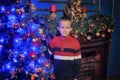 The boy next to a glowing blue Christmas tree and fireplace Royalty Free Stock Photo