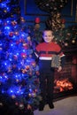 The boy next to a glowing blue Christmas tree and fireplace Royalty Free Stock Photo