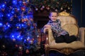 The boy next to a glowing blue Christmas tree and fireplace Royalty Free Stock Photo