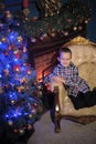 The boy next to a glowing blue Christmas tree and fireplace Royalty Free Stock Photo