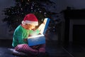 Boy open glowing present box near Christmas tree Royalty Free Stock Photo