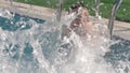 A boy in an open pool happily spattering the water