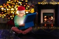 Boy open present near New Year tree and fireplace Royalty Free Stock Photo