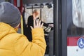 Boy in orange jacket waving saying goodbye to driver while getting off bus. Royalty Free Stock Photo