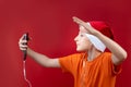 A boy in an orange T-shirt and a red Santa hat holds a phone in front of him and gestures at it Royalty Free Stock Photo