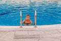 Boy in an outdoor blue pool looking at the camera