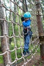 Boy overcoming mesh obstacle in forest adventure park Royalty Free Stock Photo