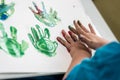 Boy painting with his hands making colorful palm prints