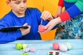 A boy paints Easter eggs with a paintbrush with the help of his older sister