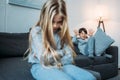 Boy in pajamas gesturing and grimacing while upset sister sitting on couch