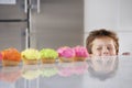 Boy Peaking Over Counter At Row Of Cupcakes Royalty Free Stock Photo