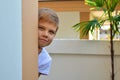 A boy peeks around the corner of the house. The child spies outdoor. Children play hide and seek outdoor