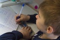 Boy with pencil writing english words by hand on traditional white notepad paper. Royalty Free Stock Photo