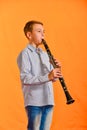 The boy performs solo at a concert, plays the clarinet on an orange background