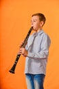 The boy performs solo at a concert, plays the clarinet on an orange background